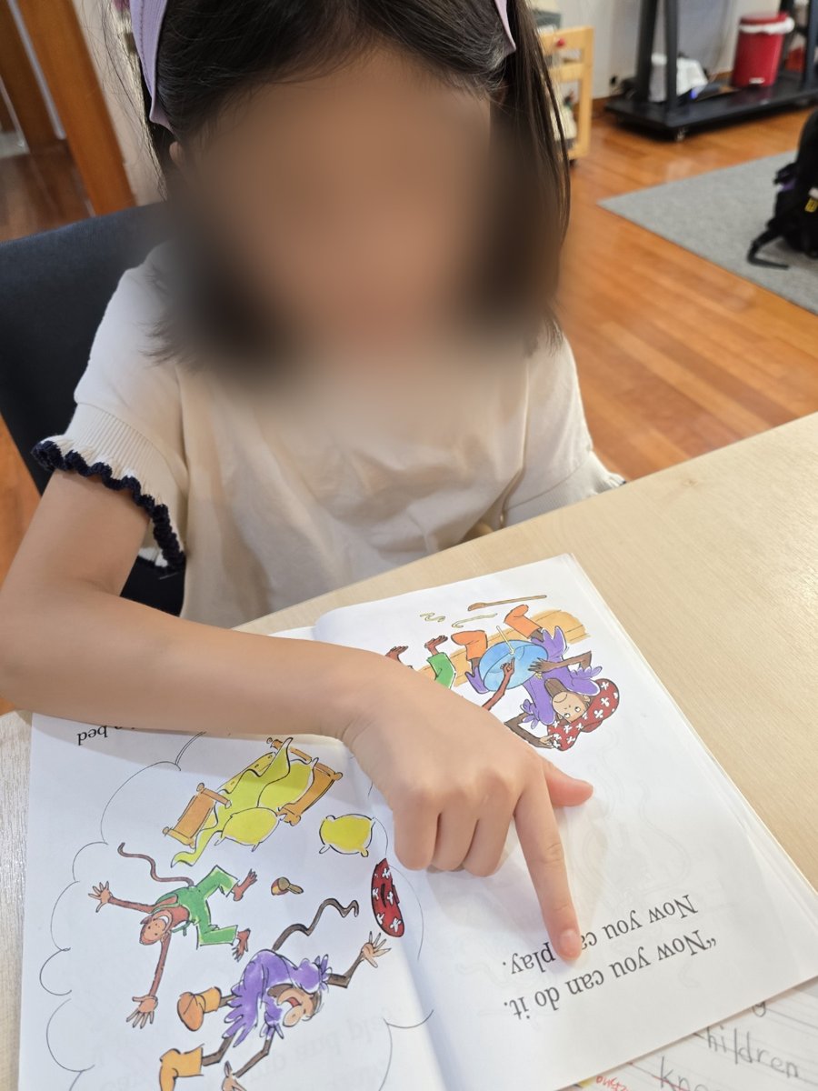 손가락으로 문장을 짚으며 그림책을 읽는 아이